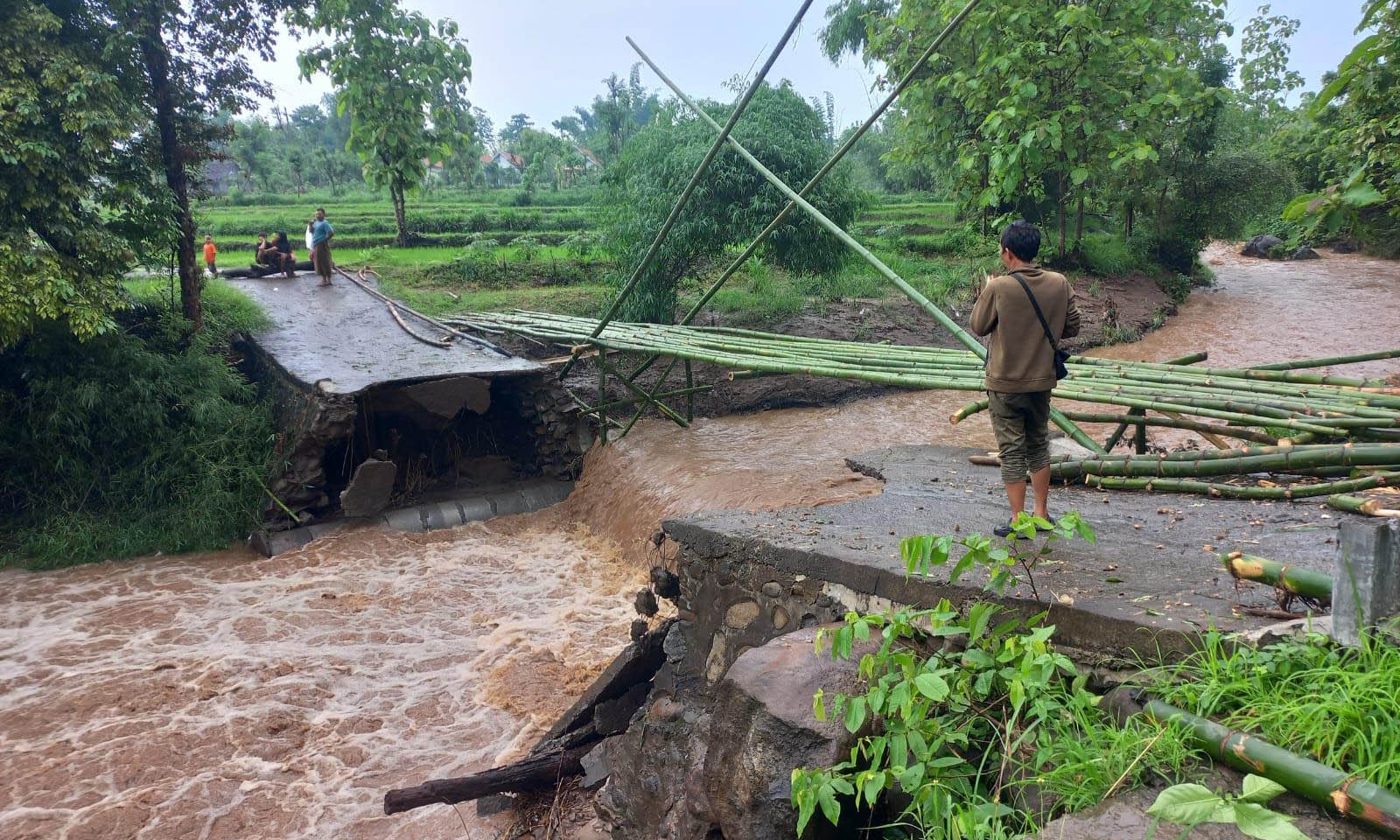 PUTUS: Sejumlah warga Desa Sumberbendo saat melihat jembatan yang putus akibat diterjang banjir, Rabu (1/12)