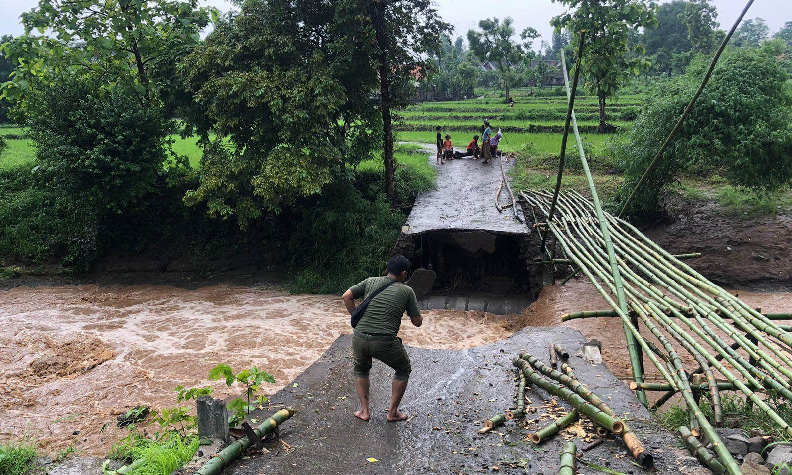 PUTUS: Sejumlah warga Desa Sumberbendo saat melihat jembatan yang putus akibat diterjang banjir, Rabu (1/12)