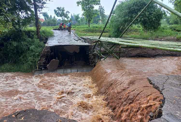 PUTUS: Sejumlah warga Desa Sumberbendo, Kecamatan Tongas, melihat jembatan yang putus akibat diterjang banjir, Rabu (1/1).