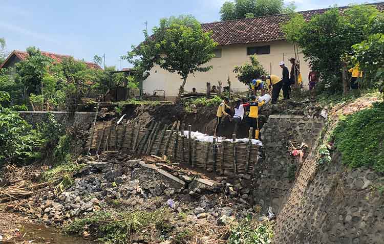 GOTONG ROYONG: Sejumlah pekerja bersama warga memasang sandbag di plengsengan Sungai Legundi, yang ambrol di Kelurahan/Kecamatan Kademangan, Kota Probolinggo, Kamis (9/1).