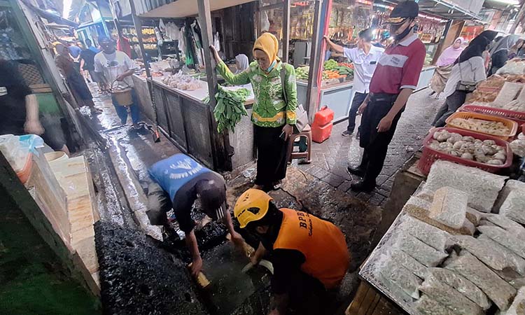 Petugas saat melakukan pengurasan bak kontrol agar air cepat surut.