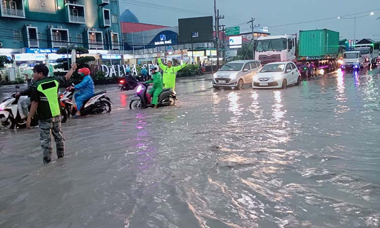 Petugas lalu lintas mengatur arus di simpang tiga PIER di Raci, Bangil yang tergenang banjir, Jumat (17/1).