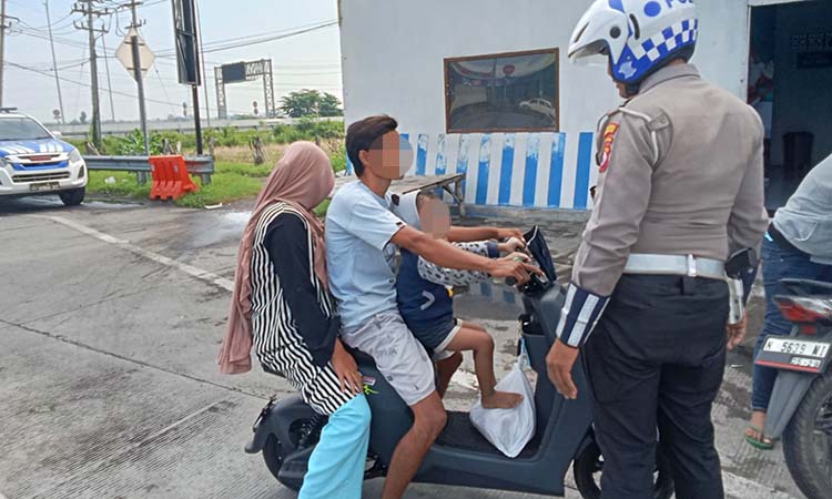 HANYA BERI IMBAUAN: Petugas Satlantas saat menghentikan sekeluarga yang menaiki sepeda listrik di kawasan jalur pantura Gending. (Achmad Arianto/ Radar Bromo)
