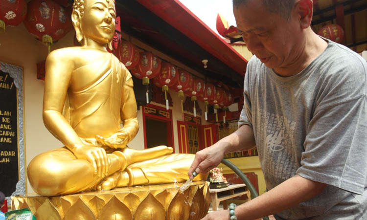 RITUAL: Erfan Sutjianto membersihkan patung-patung di klenteng Sumbernaga, Kamis (23/1) siang.