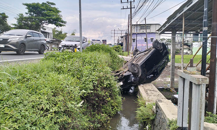 CELAKA: Mobil Sigra yang terbalik di atas parit. Insiden itu terjadi, setelah pengemudi Sigra, Khoir, hendak menghindari mobil yang tengah putar balik.