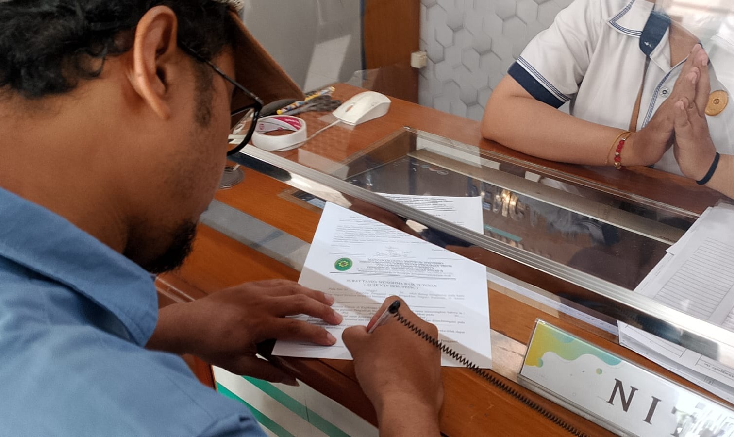 TERIMA: Deby Afandi menandatangani berkas perkara di Pengadilan Negeri Pasuruan. Ia menyatakan menerima putusan majelis hakim atas kasus hak merek yang menjeratnya.