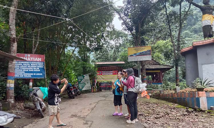 Rombongan wisman berfoto di depan patung Gajah Mada, akses masuk ke air terjun Madakaripura, Probolinggo. (Inayah Putri Maharani/ Radar Bromo)