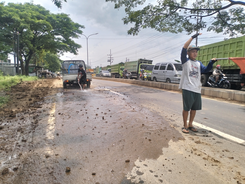 Sejumlah pekerja melakukan penyemprotan di ruas jalan yang kotor dengan material pabrik.