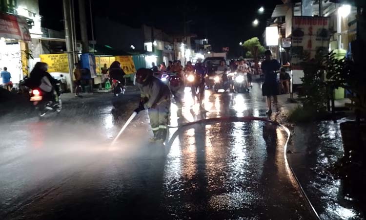 Petugas Damkar saat menyemprot ruas jalan Wahid Hasyim yang ketumpahan solar.