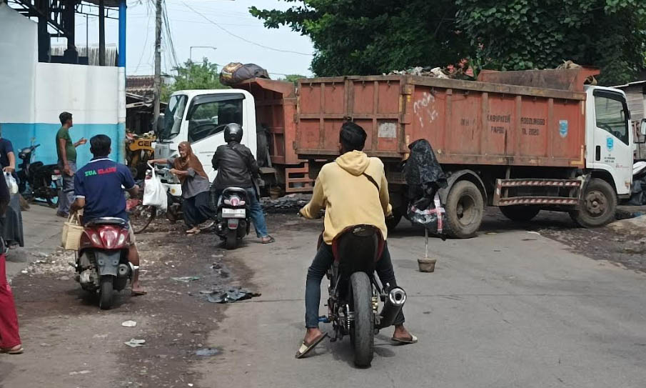 ANGKUT: Truk pengangkut sampah parkir di tengah jalan depan TPS Semampir. Selama melakukan proses pengangkutan, akses jalan harus ditutup.