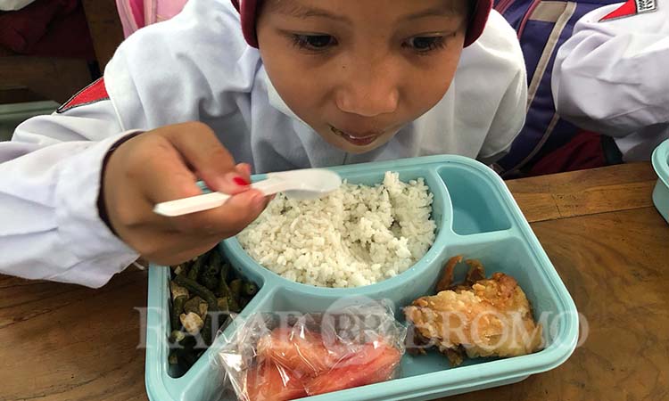 Salah satu siswi di SDN Tisnonegaran 3 asyik menyantap menu MBG terdiri atas nasi, ayam goreng, sayur kacang panjang dan buah semangka.