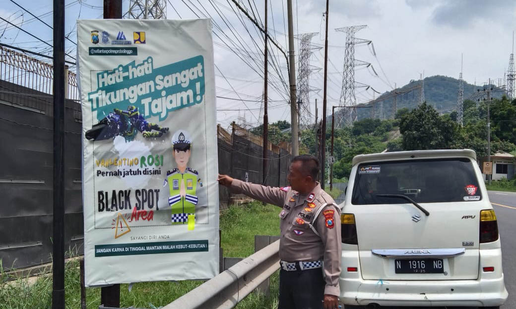 HATI-HATI: Anggota Satlantas Polres Probolinggo memasang papan himbauan di ruas jalan pantura.