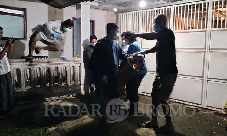 NAHAS: Petugas saat mengevakuasi jenazah korban dari dalam kamar kos di Ngadimulyo, Sukorejo, Kabupaten Pasuruan. (Rizal Syatori/ Radar Bromo)