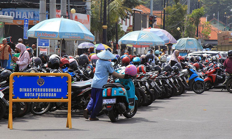 MENATA: Seorang jukir tampak menata motor warga. Untuk memaksimalkan potensi parkir, penerapan QRIS bakal direalisasikan di seluruh titik parkir Kota Pasuruan.