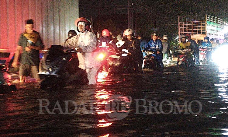 TERJANG BANJIR: Sejumlah pengendara motor menerjang banjir di Pantura Kraton, Kabupaten Pasuruan, Senin malam (24/2). (Mokhamad Zubaidillah/ Radar Bromo)