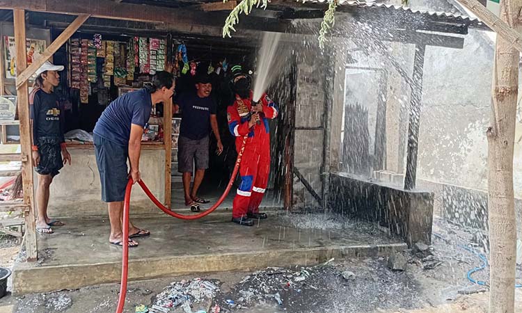 PEMBASAHAN: Pemadam kebakaran saat melakukan pembasahan di kios yang terbakar, Selasa (4/3).