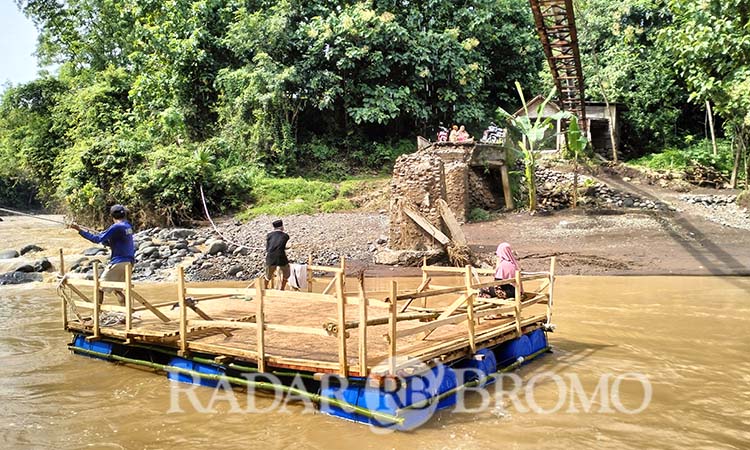 DARURAT: Warga memanfaatkan perahu getek untuk menyeberangi sungai Pekalen yang jembatannya putus usai diterjang banjir bandang. (Achmad Arianto/ Radar Bromo)