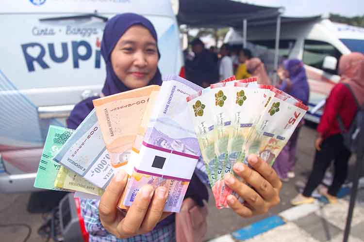 ANYAR: Salah seorang warga menunjukkan uang baru setelah ditukarkan di mobil kas keliling milik Kantor BI Perwakilan Malang di Alun-Alun Kota Pasuruan, Kamis (13/3).