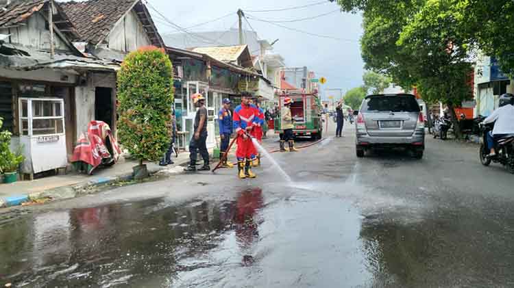 SEMPROT: Tim Damkar Satpol PP Kota Probolinggo membersihkan tumpahan solar di Jalan Panglima Sudirman-Jalan Pahlawan, Kota Probolinggo, Sabtu (15/3).