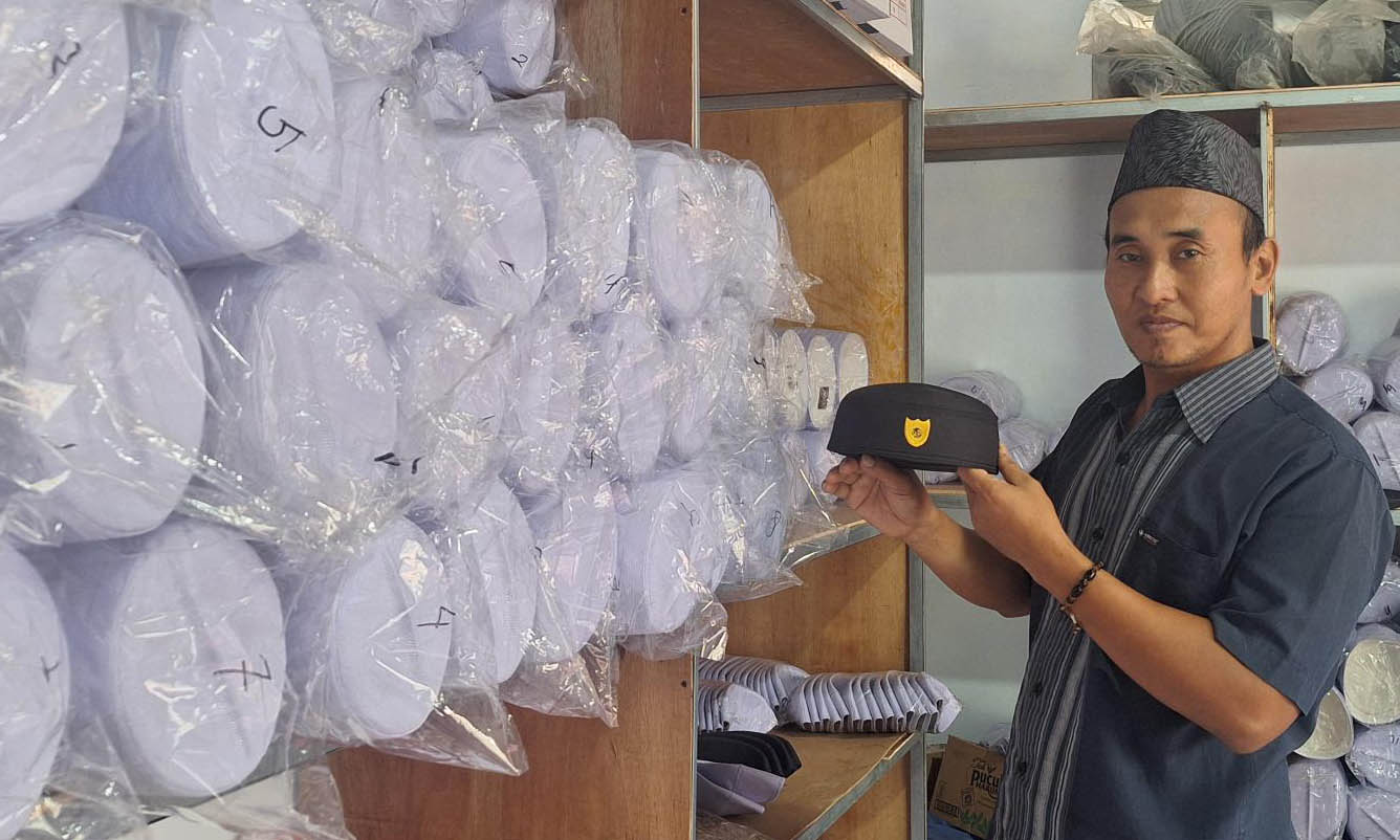 KETIBAN BERKAH:&nbsp; Bambang Hariyanto dengan tumpukan produksi kopiah di rumahnya di gudang tempat produksinya.
