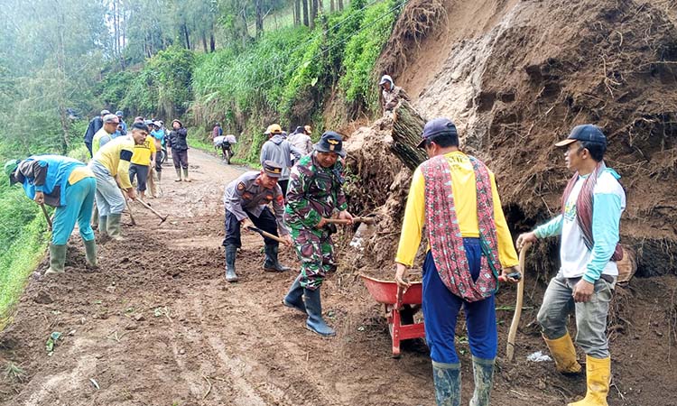 TUTUP JALAN : Petugas gabungan melakukan pembersihan material tanah longsor di Curah Kendil yang menutupi ruas jalan penghubung Kecamatan Sumber dengan Sukapura.