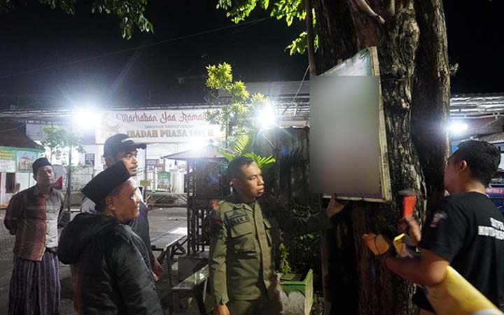Tim Satpol PP dan petugas gabungan saat mencopot salah satu spanduk yang dipasang menempel di pohon. (Famy Decta Maulida for Radar Bromo)
