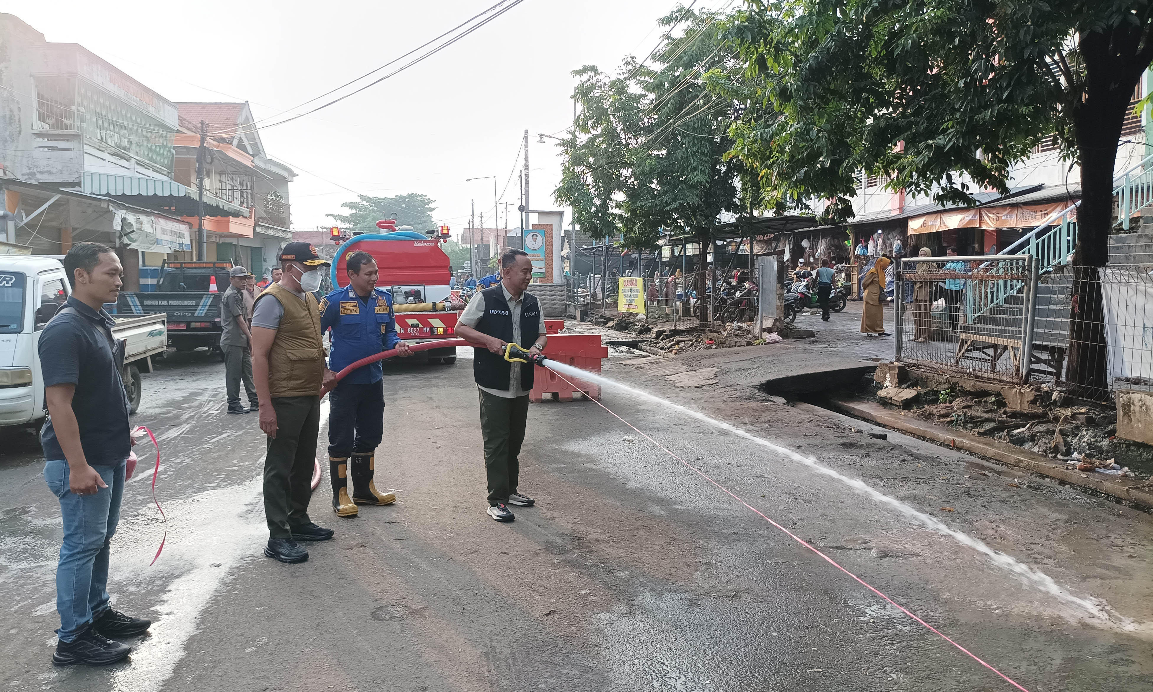 SEMPROT: Sekda Ugas Irwanto membersihkan lumpur di depan Pasar Semampir menggunakan fire engine truck, Selasa (25/3).