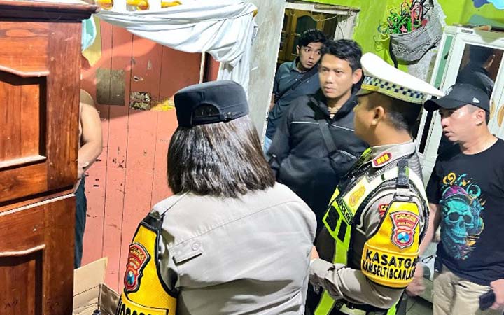 DIPERIKSA: Petugas saat memeriksa MAS di rumahnya. Ia diduga merupakan penjual miras jenis arak Bali yang berhasil digerebek polisi.