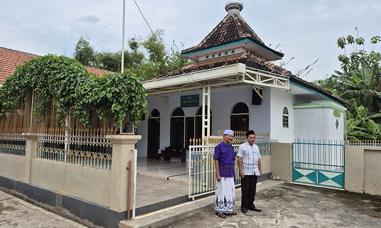 CETAK ULAMA:&nbsp;Takmir musala setempat, Abdul Qohar (baju ungu) bersama Modin Kelurahan Kepel, M. Imron berdiri di depan pagar musala.