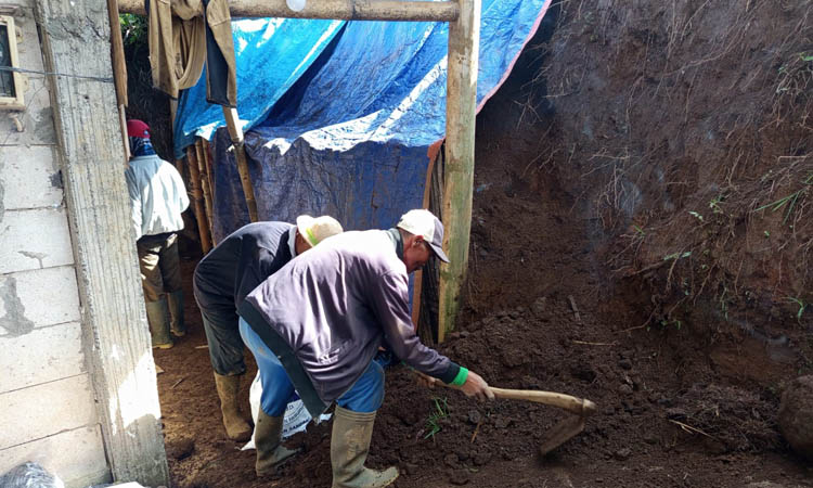 GOTONG ROYONG: Warga membersihkan material longsor yang mengenai rumah.
