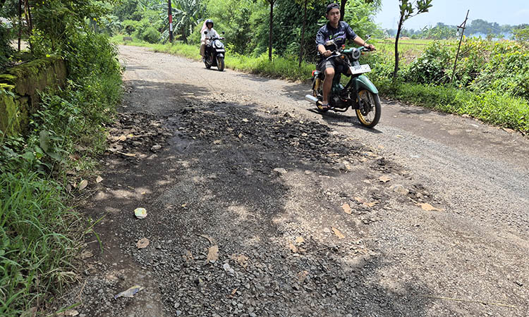 RUSAK: Pengendara motor saat melintas di jalan penghubung Jatigunting-Karangsono yang mengalami kerusakan. Jalan itu membuat warga tak nyaman.