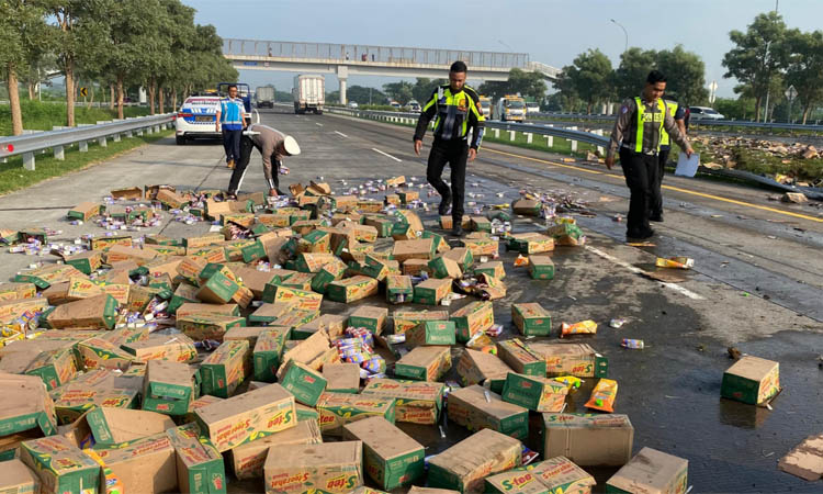 AMBURADUL: Muatan minuman kemasan yang dibawa truk wing boks sampai berhamburan keluar di jalan tol