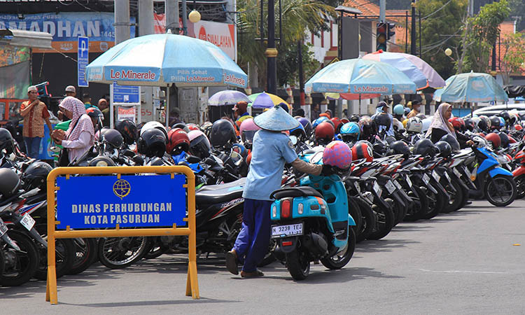 RAPIKAN: Seorang jukir sedang merapikan motor yang terparkir di kawasan Alun-Alun Kota Pasuruan.