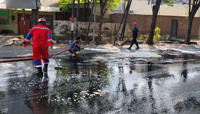 DIBERSIHKAN: Tim Damkar Kota Probolinggo saat membersihkan ceceran solar di Jalan Pahlawan, tikungan Brak ke arah utara, Sabtu (26/4). (Istimewa)