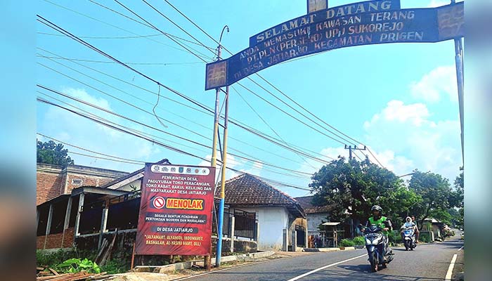 TOLAK TOKO MODERN: Banner bertuliskan menolak toko modern dipampang di dekat gapura masuk Desa Jatiarjo, Prigen, Kabupaten Pasuruan. (M Busthomi/ Radar Bromo)