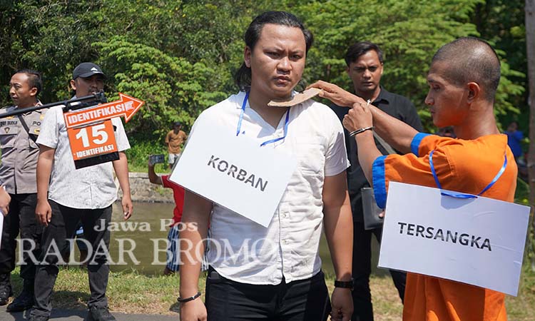 REKONSTRUKSI: Tersangka Didik saat memperagakan adegan menghabisi istri yang telah pisah ranjang dengannya di Alas Malang Probolinggo. (Achmad Arianto/ Radar Bromo)