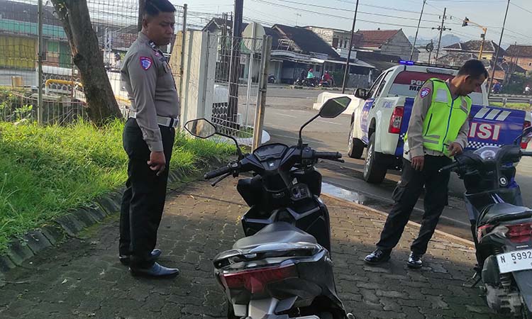 NAHAS: Petugas kepolisian saat mengamankan dua motor yang terlibat kecelakaan maut dipicu jalan berlubang di Purwosari, Pasuruan (2/5). (Istimewa)