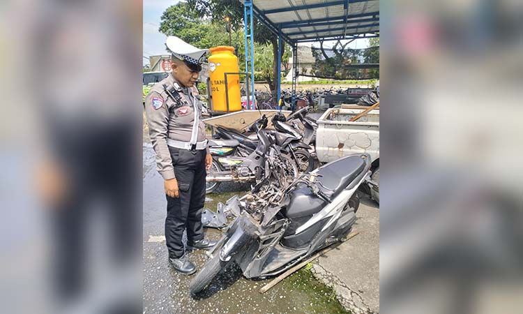 BARANG BUKTI: Petugas unit Lantas Polsek Pandaan menunjukkan motor korban yang alami ringsek parah pada bagian depannya usai menyeruduk truk.