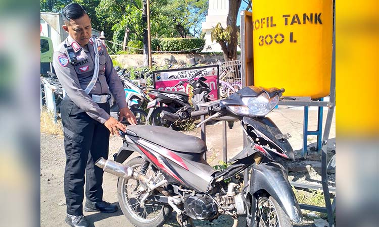BARANG BUKTI: Anggota Satlantas Polres Pasuruan menunjukkan motor korban yang rusak setelah kecelakaan.