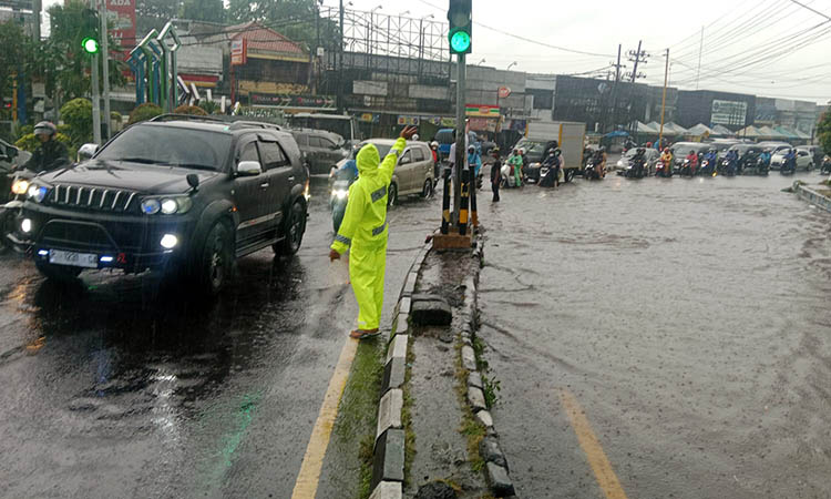 MENGGENANG: Petugas Unitlantas Polsek Purwosari saat mengatur arus lalu lintas imbas genangan air di jalan Malang-Surabaya.