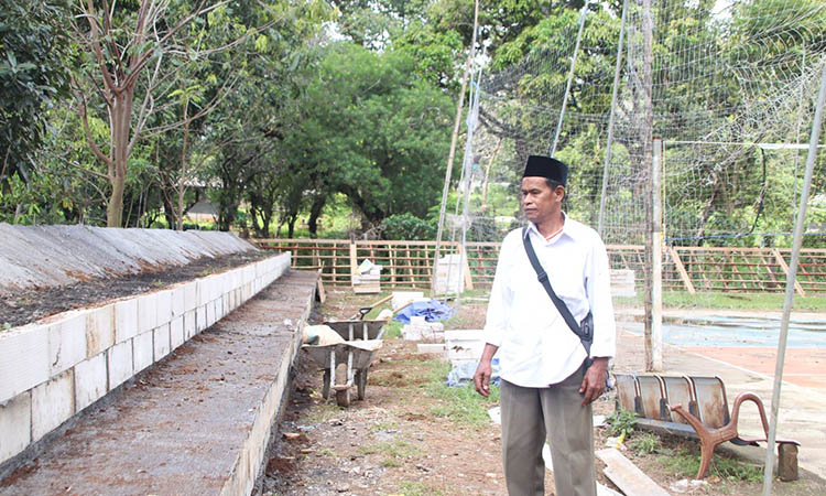 PENGERJAAN: Kasi Kesra Desa Branggah, Sumari saat mengecek pembanguann tribun lapangan bola voli di Dusun Krajan, Desa Branggah, Kecamatan Lumajang.