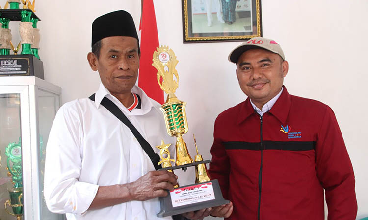 MENANG: Kasi Kesra Desa Branggah, Sumari (kiri) dan Operator Desa Branggah, Suwanda (kanan) membawa piala juara 1 lomba bola voli tingkat kecamatan.