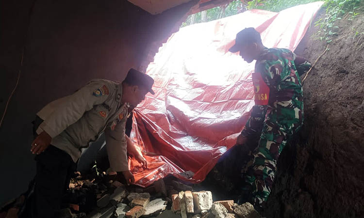 PASANG: Pemasangan terpal yang dilakukan petugas gabungan pada bagian longsoran tanah yang menjebolkan tembok BUMDes Kemiri. Longsor itu dipicu, hujan deras yang melanda serta kontur tanah yang lemah.