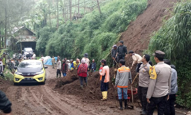 EVAKUASI: Petugas gabungan bersama warga saat berusaha melakukan evakuasi terhadap material longsor yang menutupi jalan.
