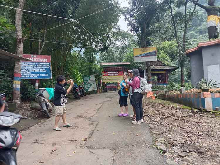 BERWISATA: Sejumlah wisatawan berfoto di depan pintu masuk Air Terjun Madakapura, Kecamatan Lumbang, yang masih ditutup.