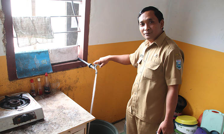 LANCAR: Sekretaris Desa Sapih, Tonawar saat menunjukkan lancarnya air yang menggunakan water meter dari Bumdes, Senin (19/5).