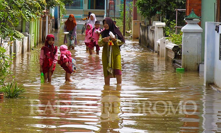 TERENDAM: Sejumlah warga melintasi jalan desa Bandaran, Winongan yang terendam banjir. (Mokhamad Zubaidillah/ Radar Bromo)
