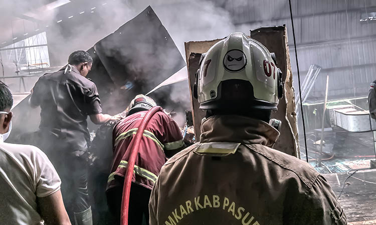 PEMBASAHAN: Personel damkar melakukan upaya pemadaman kebakaran gudang cold storage di PT Winaros Kawula Bahari, Desa Cangkringmalang, Kecamatan Beji.