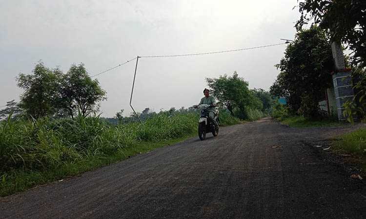 SEMAKIN NYAMAN: Salah seorang pengendara sepeda motor saat melawati jalanan di depan balai desa yang rampung diaspal tahun ini.