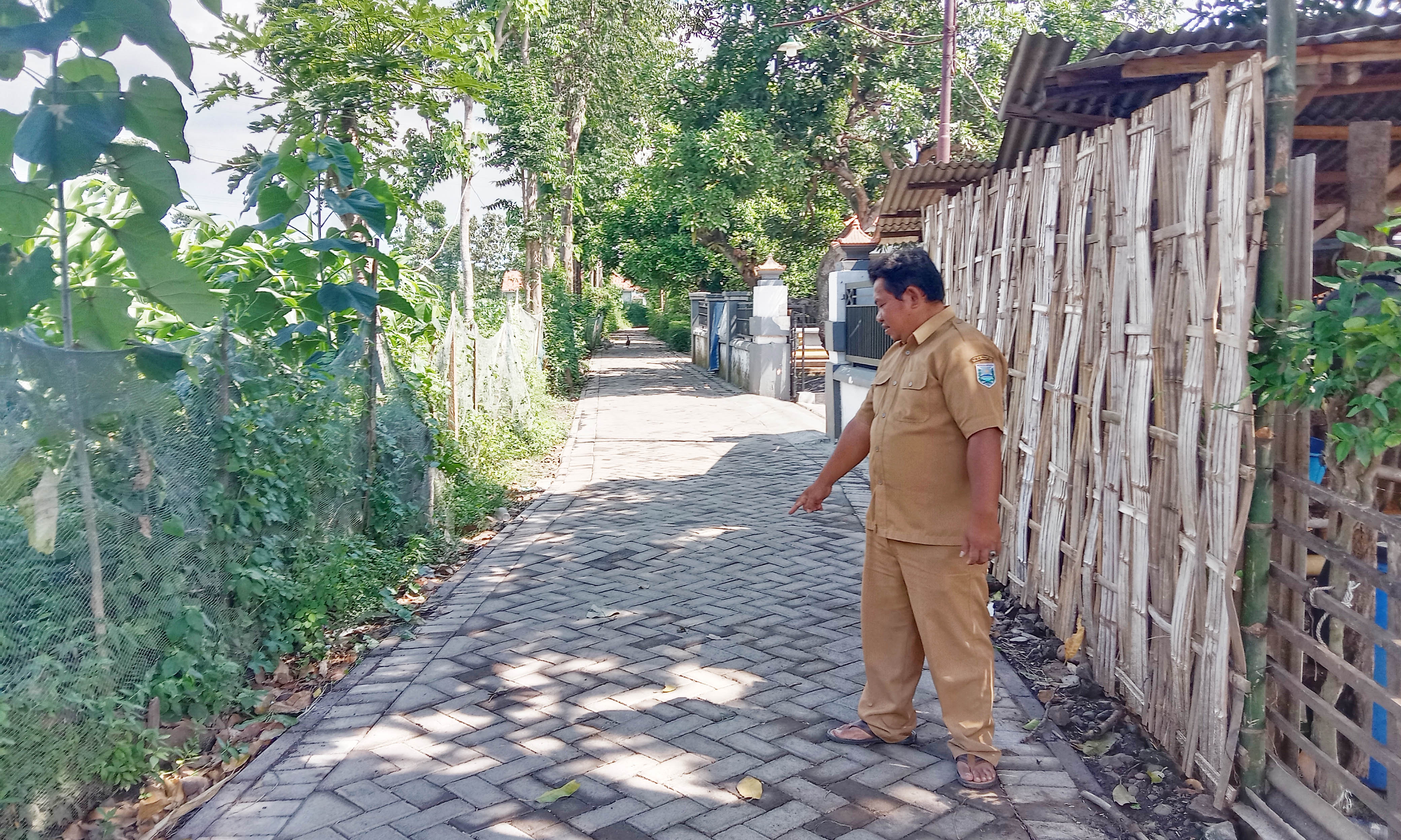 NYAMAN: Perangkat Desa Sepuh Gembol Mulyadi saat menunjukkan pavingisasi di Dusun Jati RT 04/ RW 01 yang telah rampung. Kini jalan usaha tani itu semakin ny